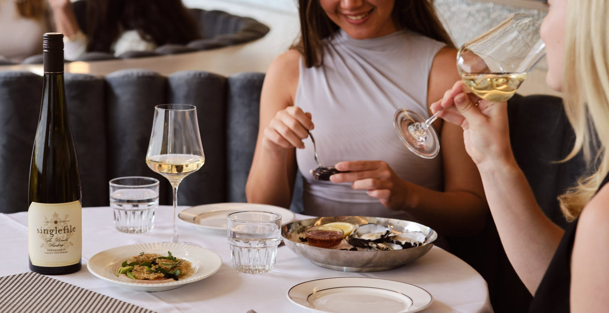 Three diners sharing plates with a bottle of Singlefile white at a Melbourne BYO restaurant