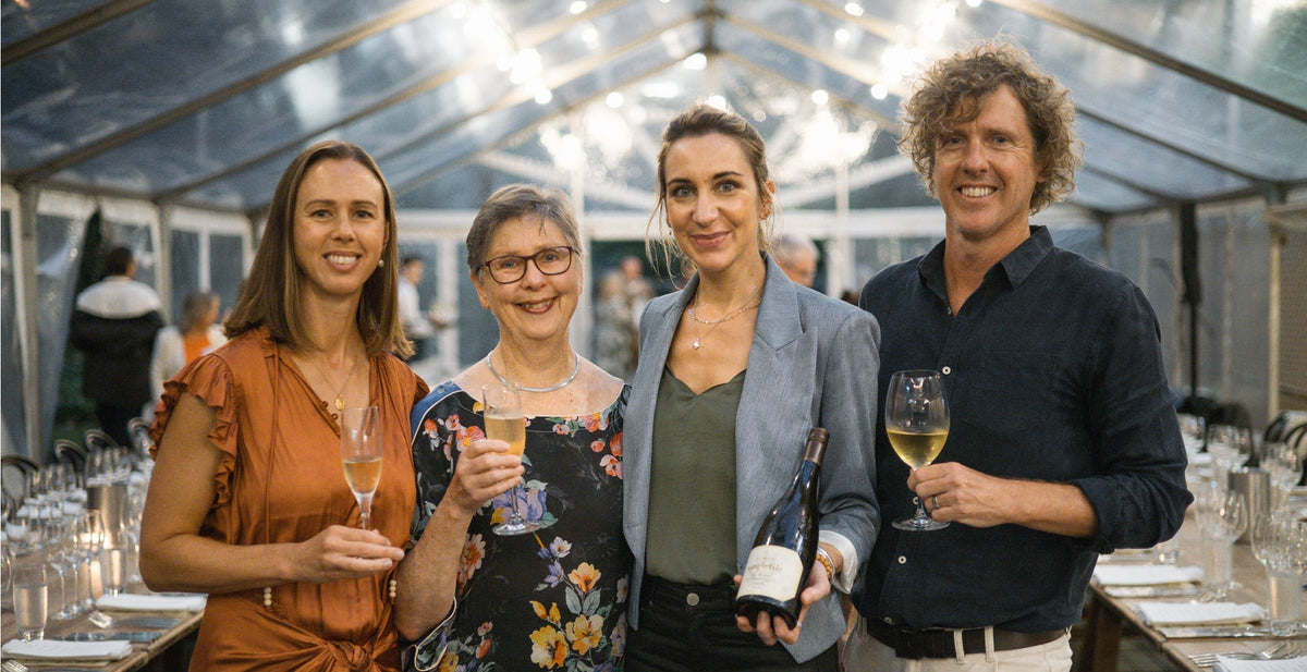 Four guests with glasses and bottles of Singlefile wine at a marquee event