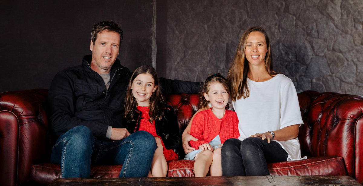 Pat, Pam and their two daughters on a chesterfield couch at the Cellar Door