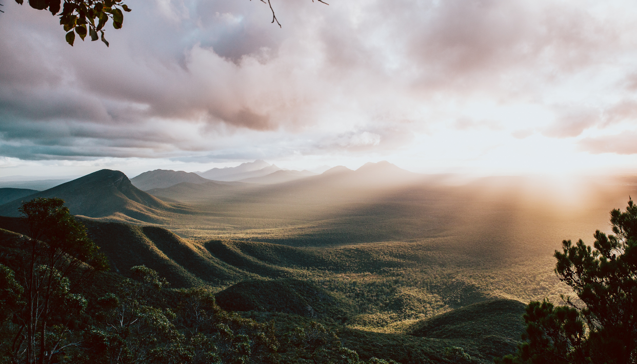 Sunlight filtering through clouds over a mountainous landscape