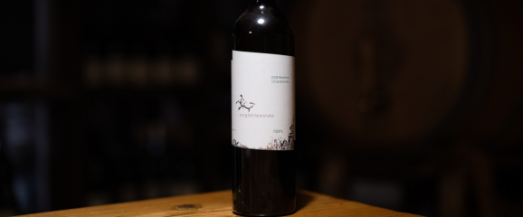 Wine bottle with a label on a wooden surface against a dark background