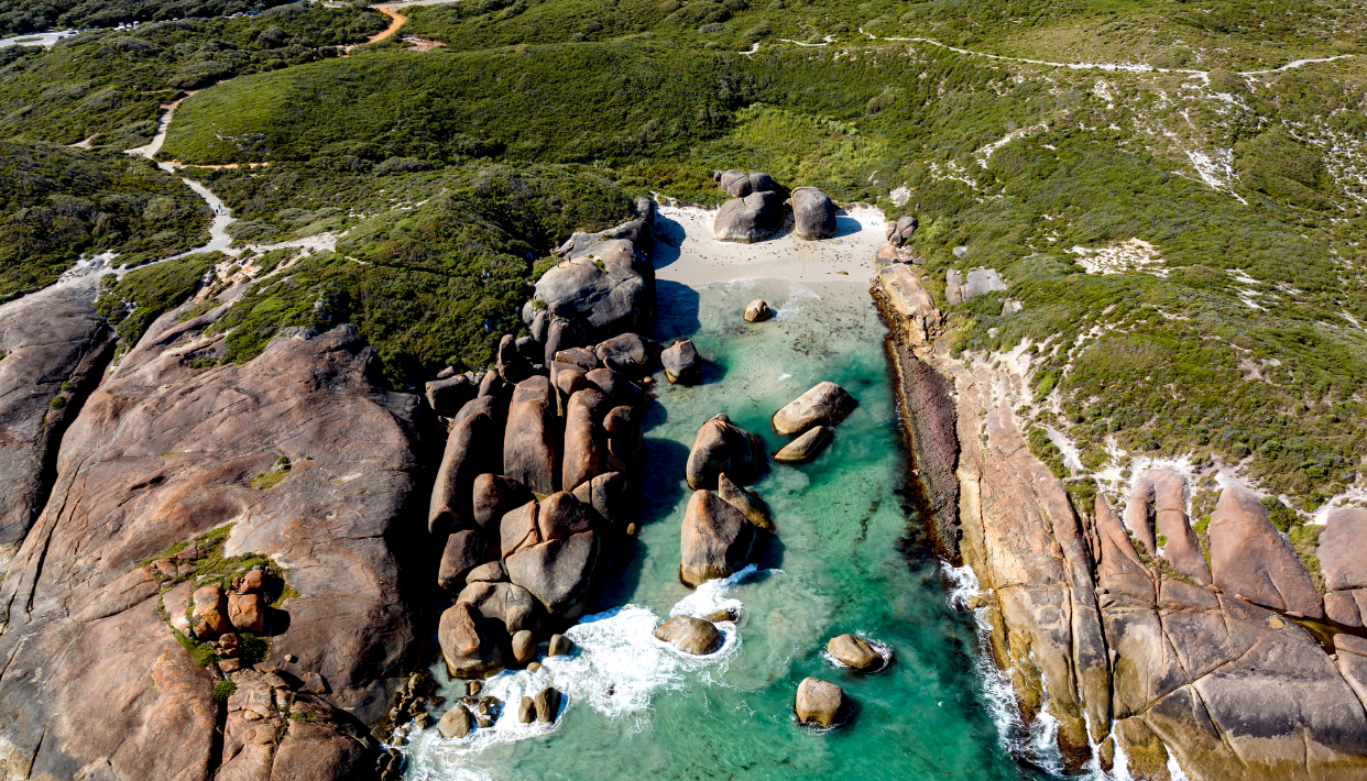 Aerial view of rocky coastline with clear water and greenery