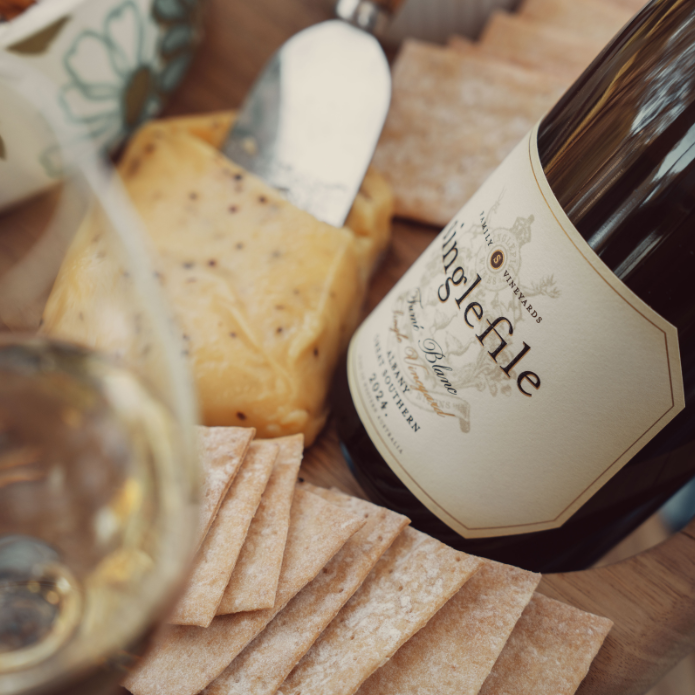 Wine bottle with crackers and a glass of wine on a wooden surface