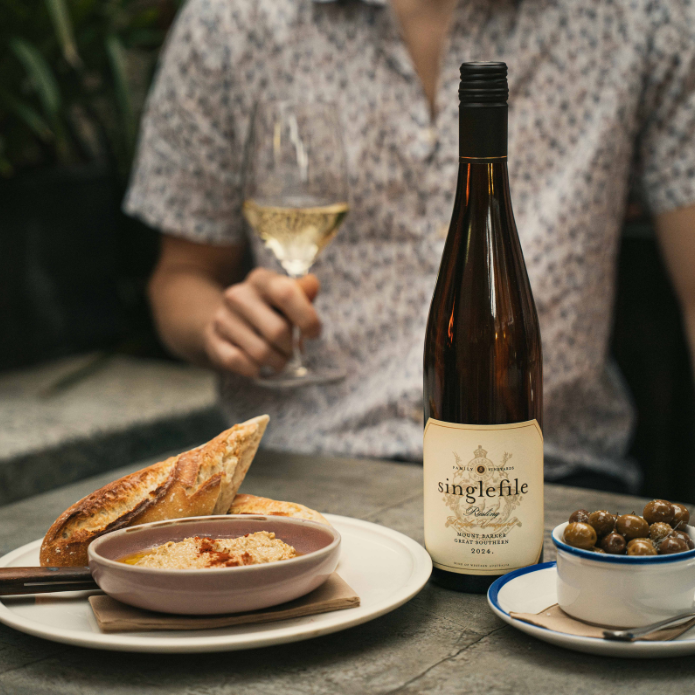 Bottle of Singlefile Riesling with a glass of wine and food on a table