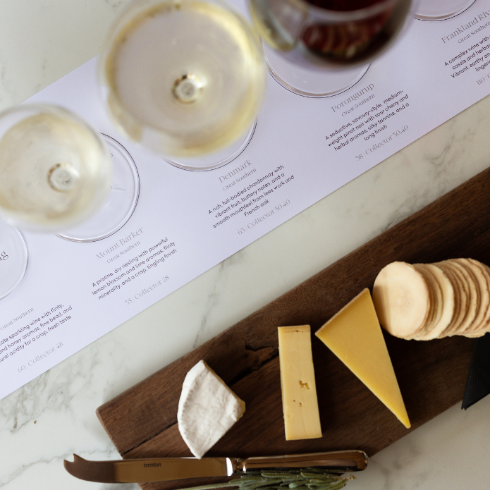 Cheese platter with wine glasses and a menu on a marble surface