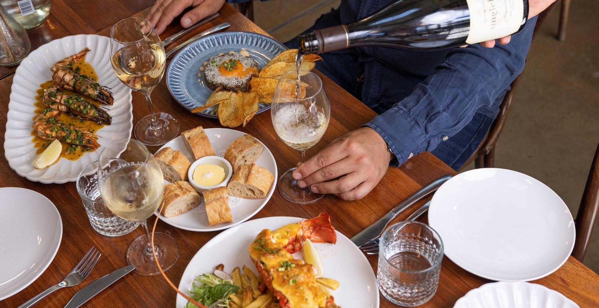 Pouring a glass of wine on a table laid with food