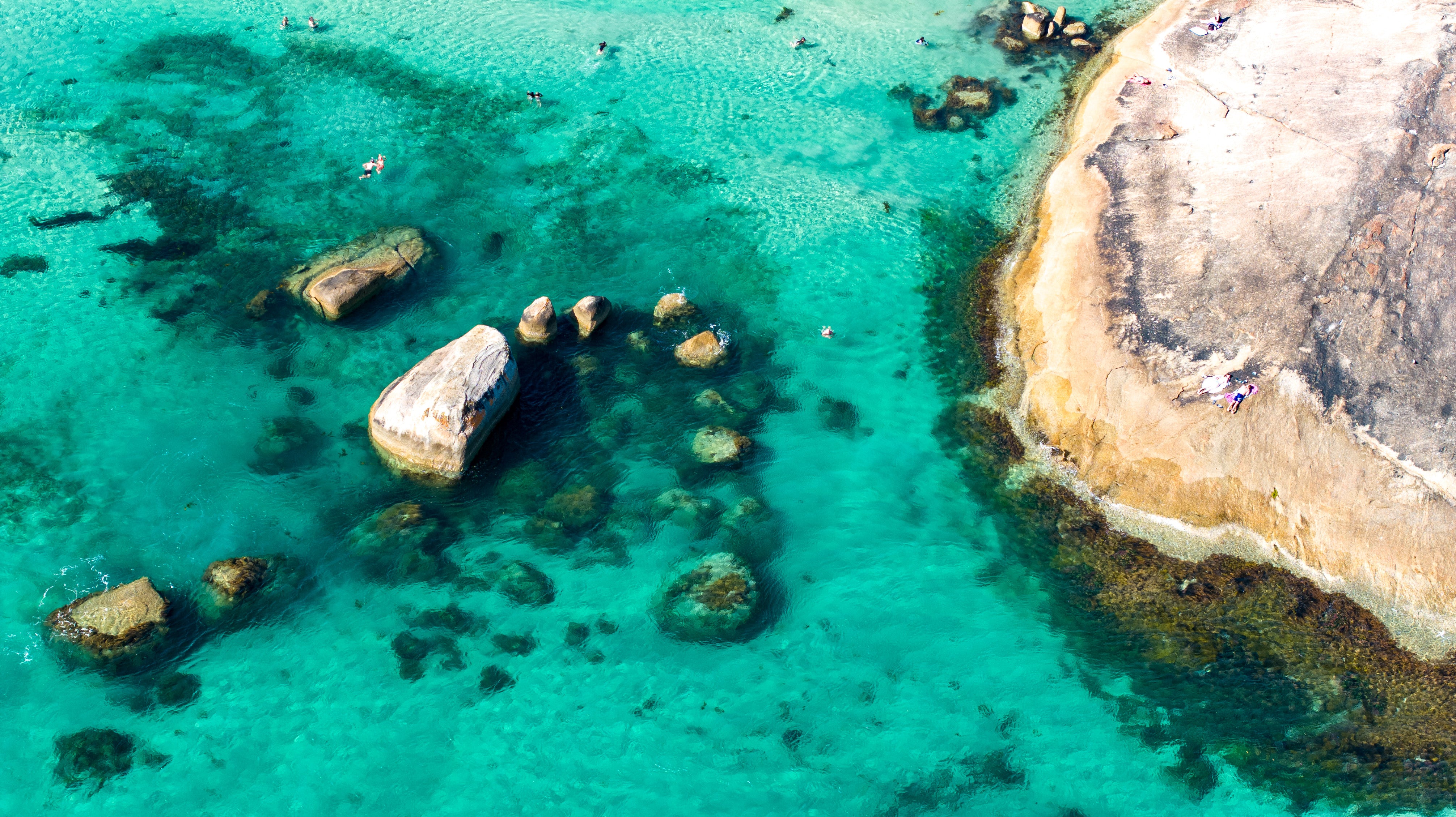 Aerial view of a rocky coastline with clear turquoise water.