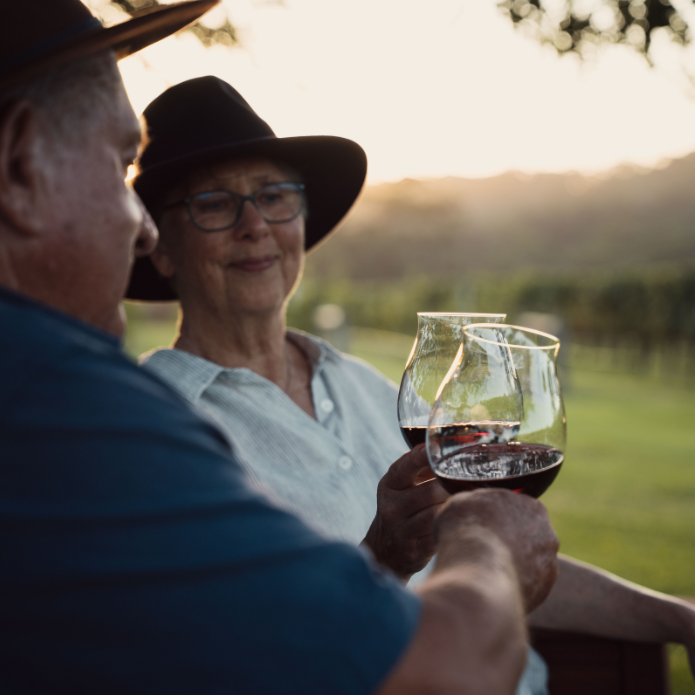Two people toasting with wine glasses in a scenic outdoor setting.