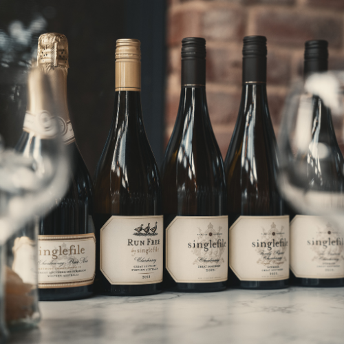 Bottles of wine with glasses displayed on a bench