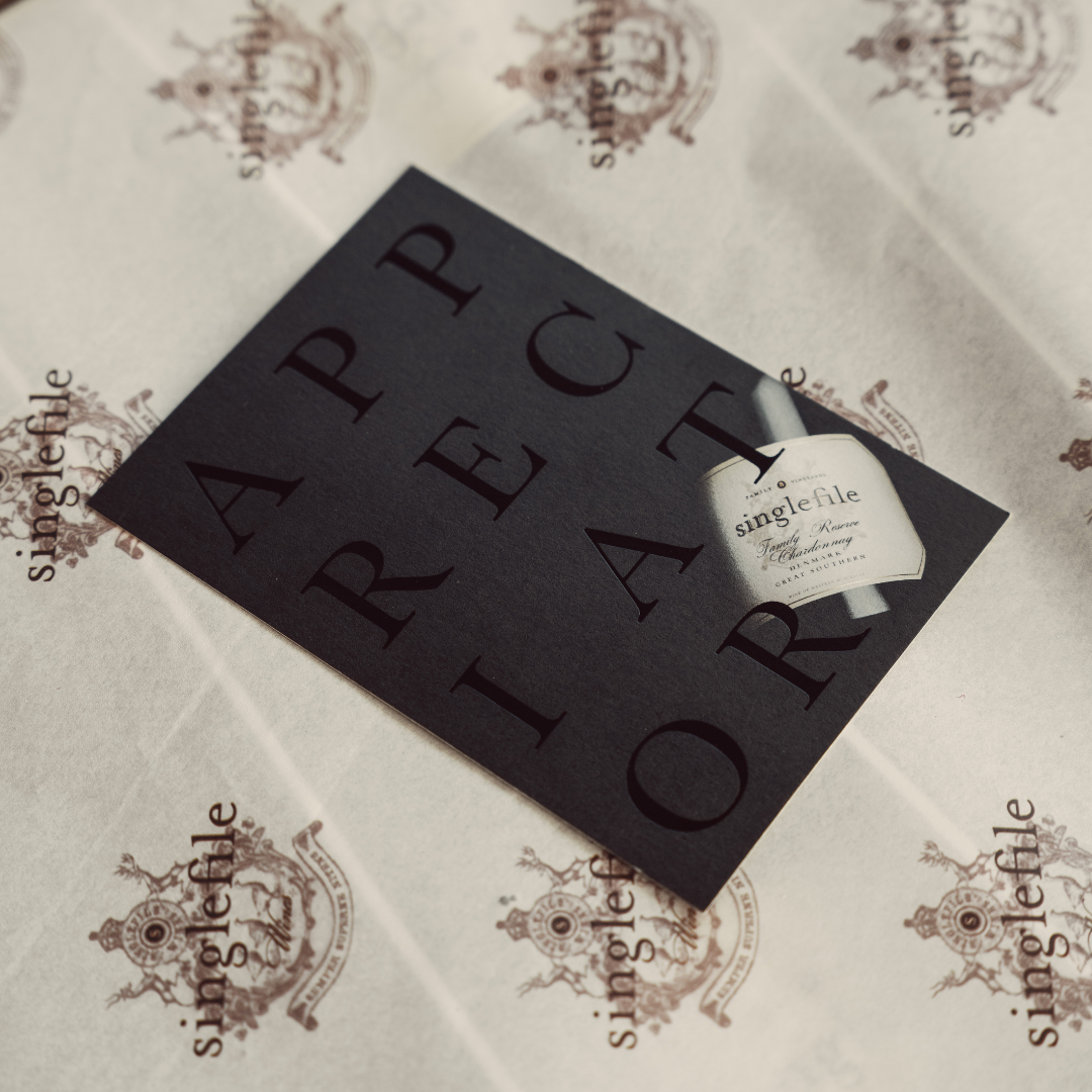 White bottle with black label on a decorative surface with 'singlefile' branding.