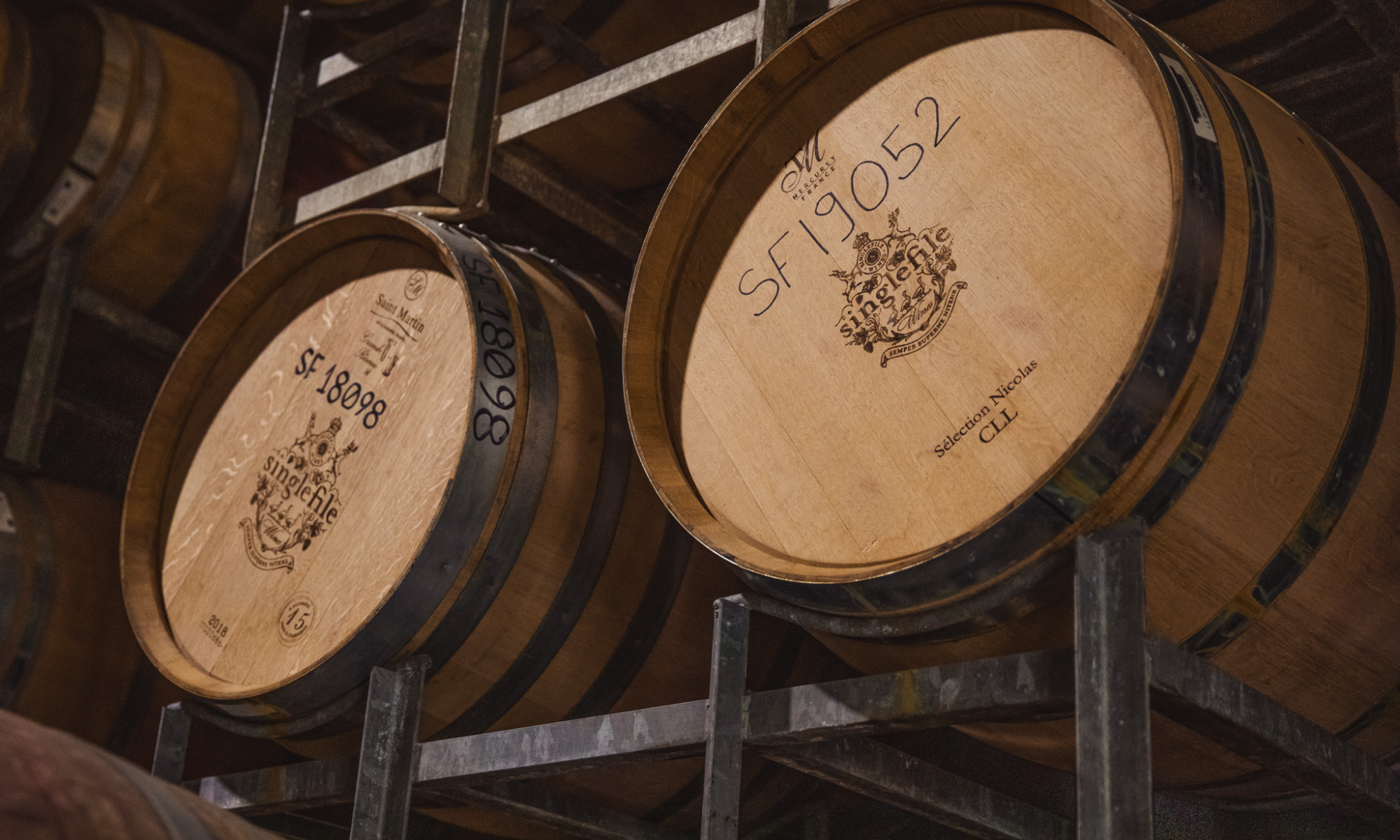 Wooden barrels with visible age markings in a storage rack.