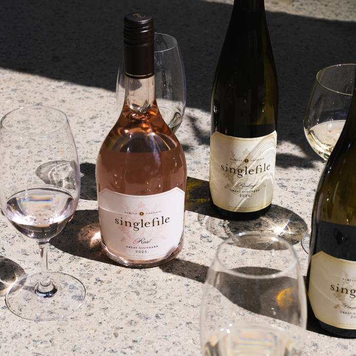 Wine bottles and glasses with 'singlefile' branding on a stone surface