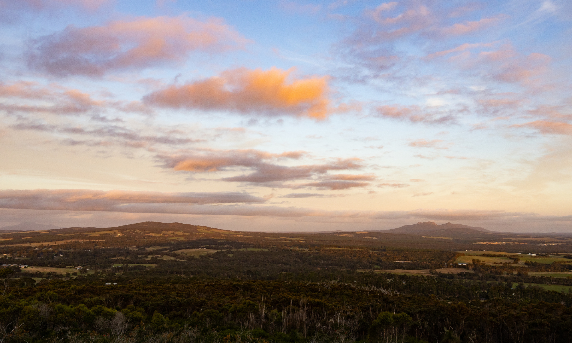 Scenic view of a landscape with hills and a colorful sky at sunset.
