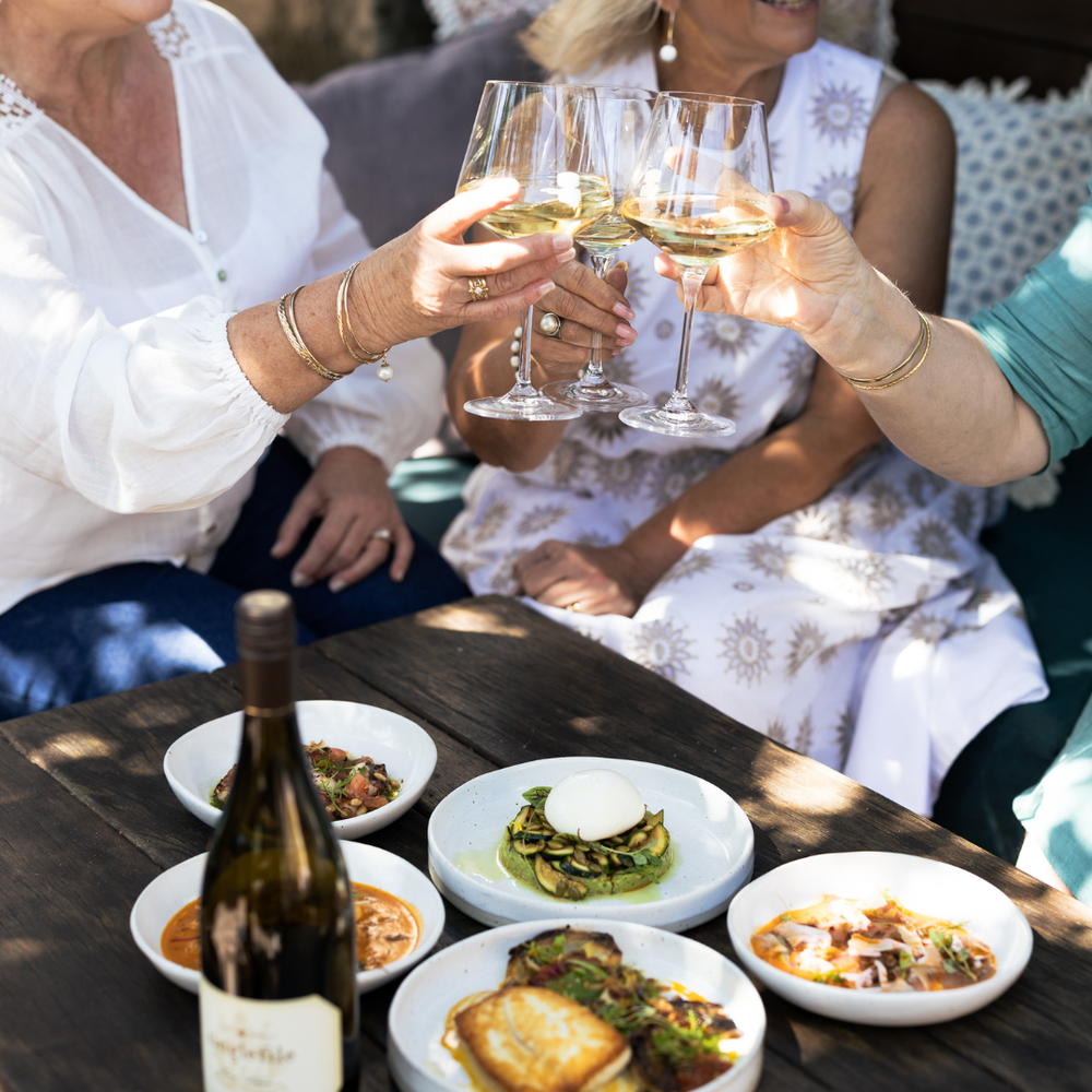 People toasting with wine glasses at a table with food