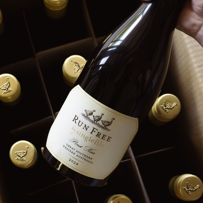 Wine bottle labeled 'Run Free' in a wine rack with gold bottle caps.