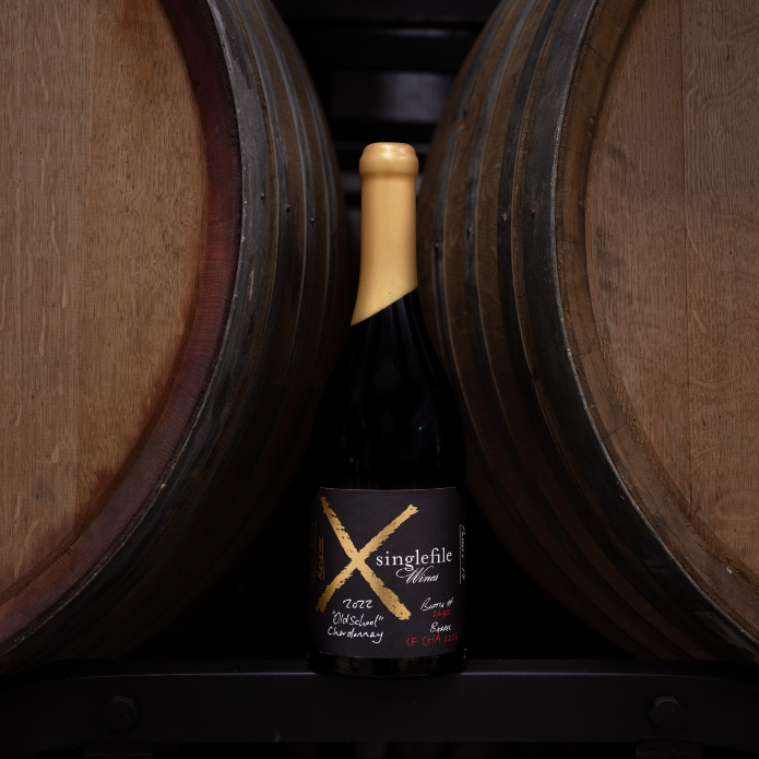 Wine bottle with 'singlefile wine' label between two wooden barrels