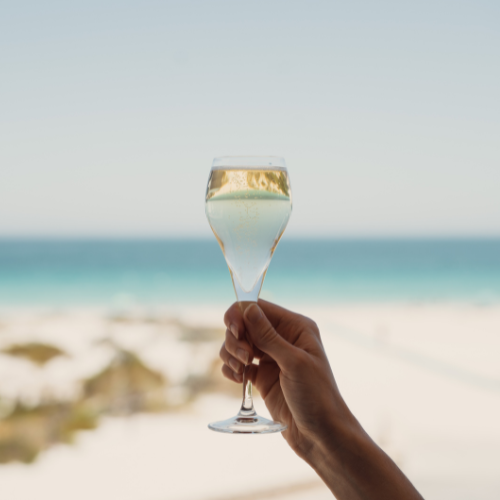 Glass of sparkling wine in front of a beach