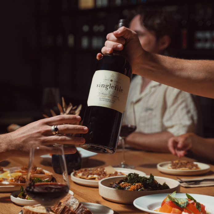 Magnum bottle of wine being passed between people