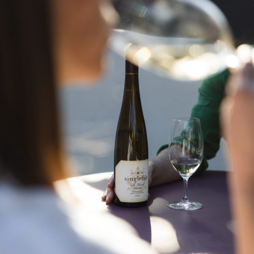 White wine bottle and a person drinking a glass of wine