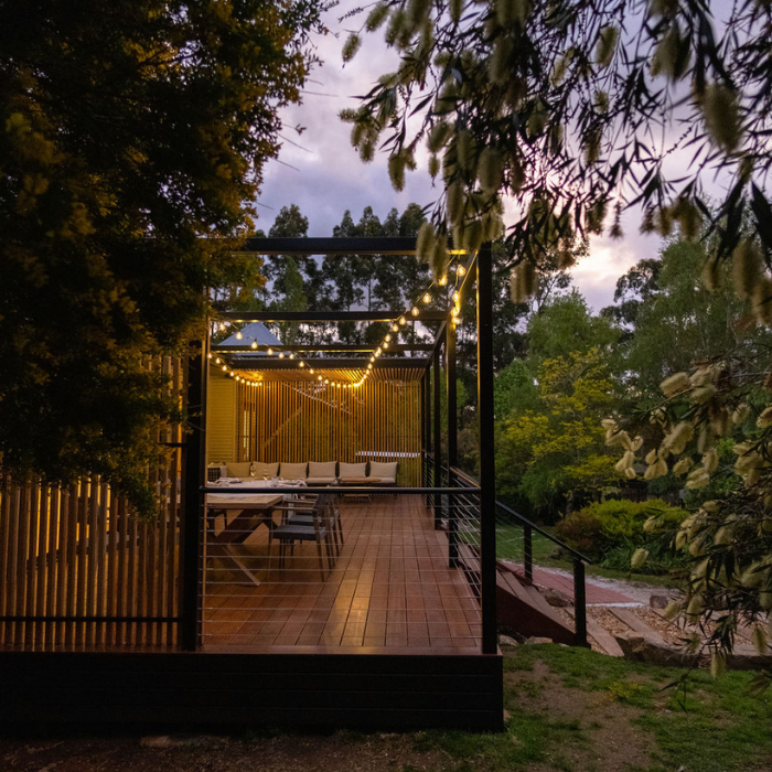 Wooden deck with string lights surrounded by trees at dusk