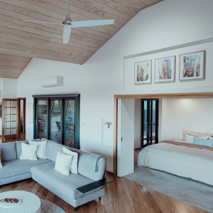 Modern living room with gray sectional sofa, wooden floor, and ceiling fan.