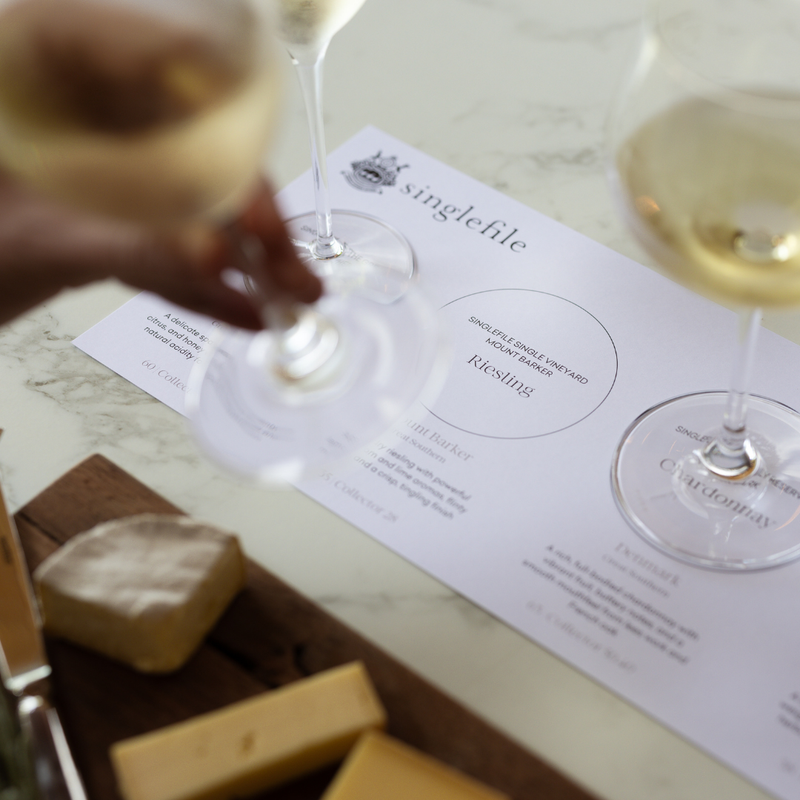 Wine tasting setup with glasses and a 'singlefile' label on a marble surface.